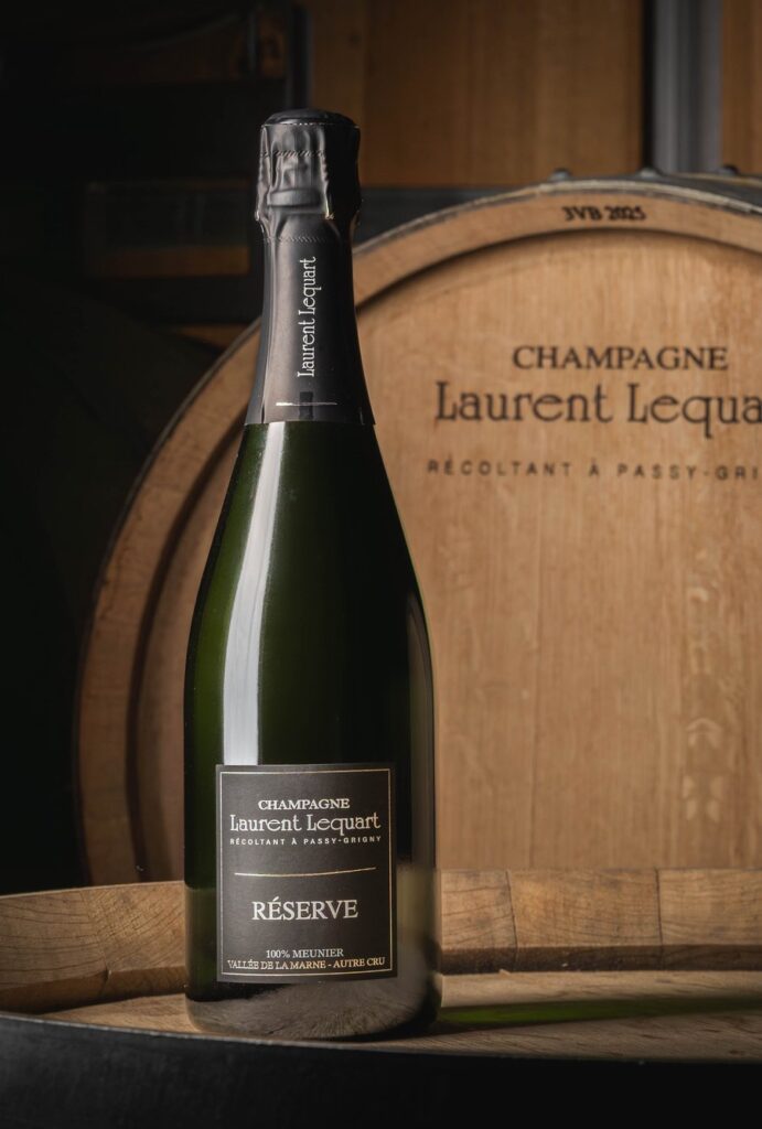Bouteille de la cuvée Réserve devant un foudre gravé Champagne Laurent Lequart